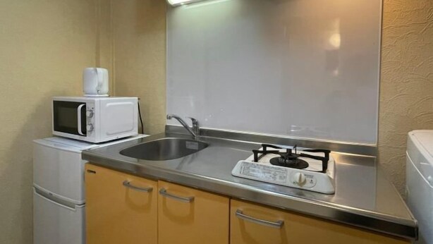 A compact kitchen with a microwave, sink, stove, and a small refrigerator. - Tasone Stay OSAKA SL610 (Osaka)