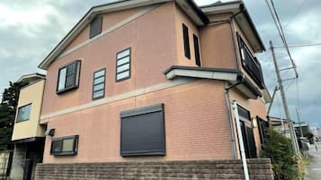 Un edificio residenziale a due piani con facciata in mattoni, un portone per garage e un vialetto visibile.
