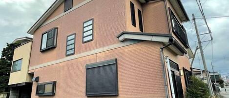 Un edificio residenziale a due piani con facciata in mattoni, un portone per garage e un vialetto visibile.