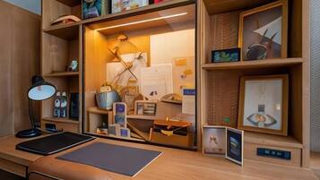 A wooden desk with a laptop, a desk lamp, and a framed picture.