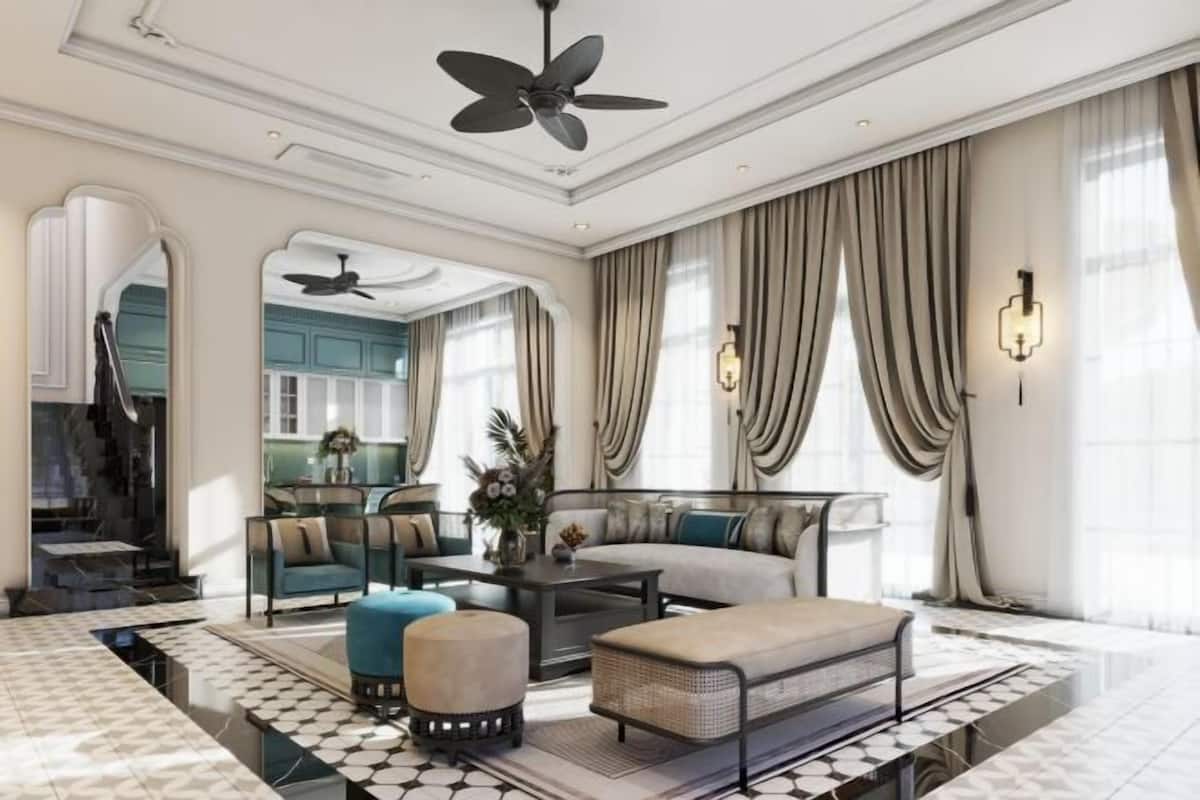 Un salon spacieux comprenant un canapé, un pouf et une table basse, ainsi qu’un ventilateur de plafond et une vue sur la cuisine.