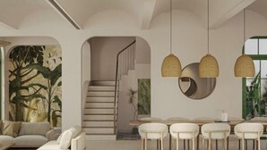 Um interior moderno com uma escada, uma área de jantar com mesa redonda e cadeiras, e um sofá.