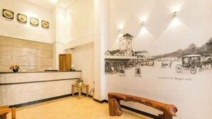 A reception area with a marble floor, a wooden bench, a reception desk, and a wall with a historical mural.