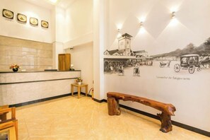 Ein Empfangsbereich mit Theke, einer Holzbank und einer Wand mit historischen Illustrationen.