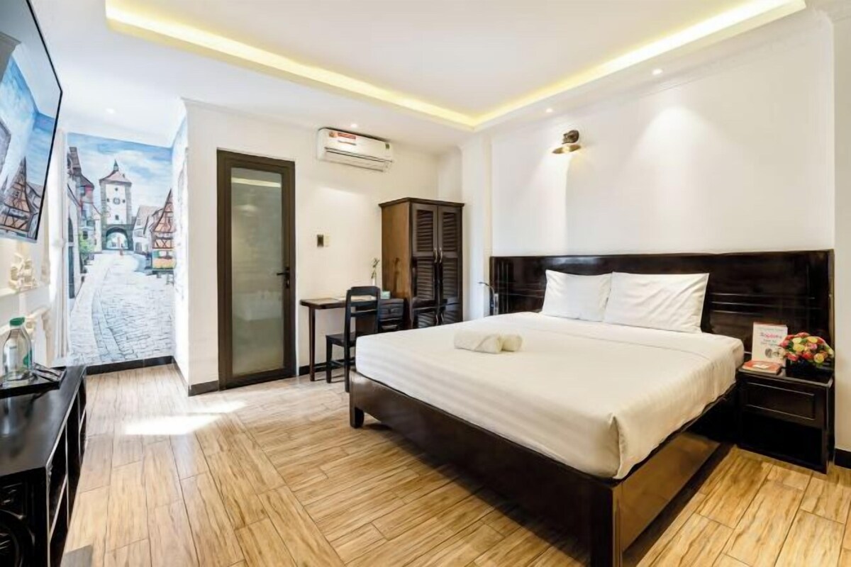 A hotel room with a large bed, a desk, and a chair.