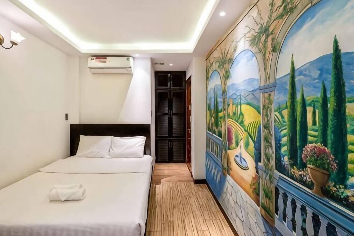 Una habitación de hotel con una cama, un cuadro y una puerta que da a otra habitación.