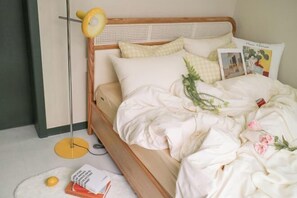 A bed with a wooden headboard, white bedding, a floor lamp, and a few books on the floor. - Hongik Univ. Station Romantic Rooftop House (Seoul)