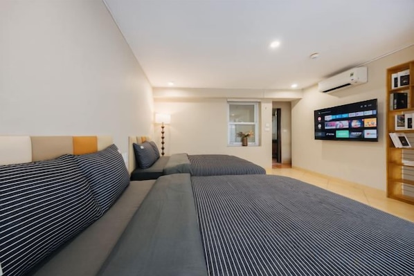 A modern hotel room with a bed, a TV, and a bookshelf. - VietHOME - 22 Pho Hue - Apartment 702 (Hanoi)