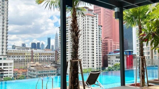 A rooftop pool with a view of a cityscape, including tall buildings and palm trees. - TR Residence Titiwangsa By Iconique (Kuala Lumpur)