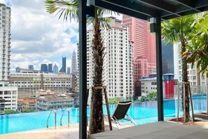 A rooftop pool with a view of a cityscape, including tall buildings and palm trees. - TR Residence Titiwangsa By Iconique (Kuala Lumpur)