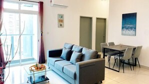 A modern living room with a sofa, dining table, chairs, and artwork on the walls. - TR Residence Titiwangsa By Iconique (Kuala Lumpur)