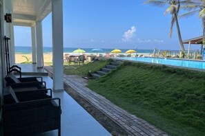 A poolside area with a view of the beach, outdoor seating, and umbrellas. - Pearl Island Beach Hotel (Hikkaduwa)
