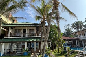 A two-story building with a balcony, a swimming pool, and palm trees. - Pearl Island Beach Hotel (Hikkaduwa)