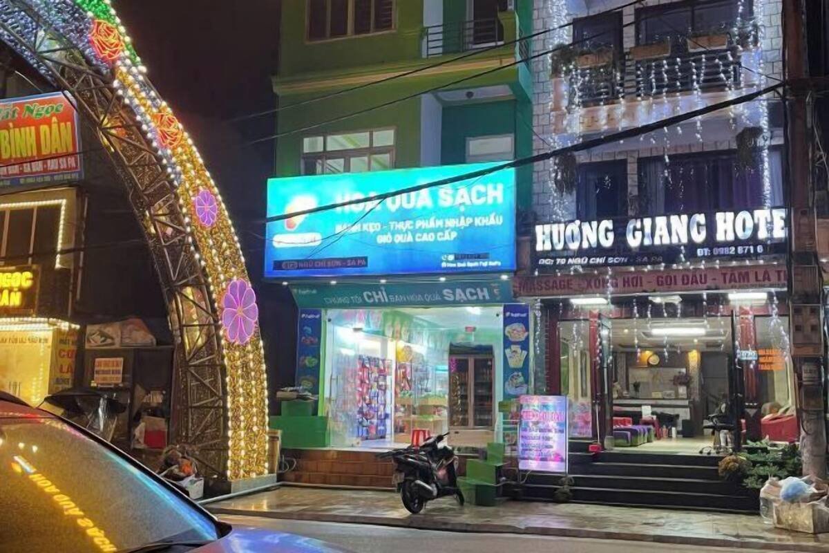 A building with a sign for 'Hương Dương Sach' and 'Hương Giang Hotel' with a motorcycle parked in front.