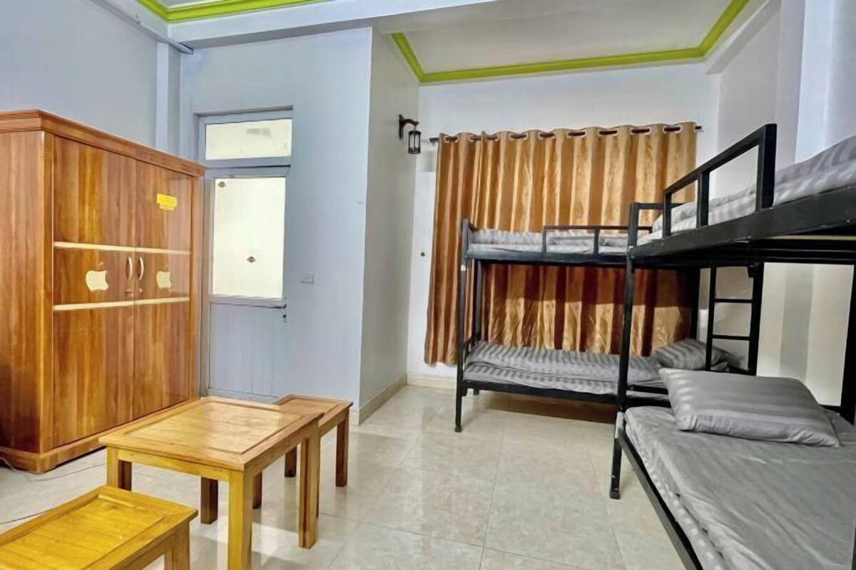 A room with bunk beds, a wooden wardrobe, and a small table.