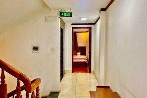 A hotel hallway with a staircase, a bed in the background, and a sign indicating the direction to the elevator. - Fuji sapa central hostel (TT. Sa Pa)
