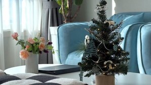 A small Christmas tree with ornaments and lights on a table in a room with a blue couch and a plant. - EunhasuD&M Residence Hotel (Daejeon)