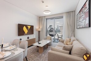 Habitación de hotel moderna con comedor, sofá, sillón colgante y vista a la ciudad a través de amplias ventanas.