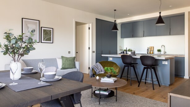 A modern kitchen with grey cabinets, a central island, and bar stools. - Native Verso (London)