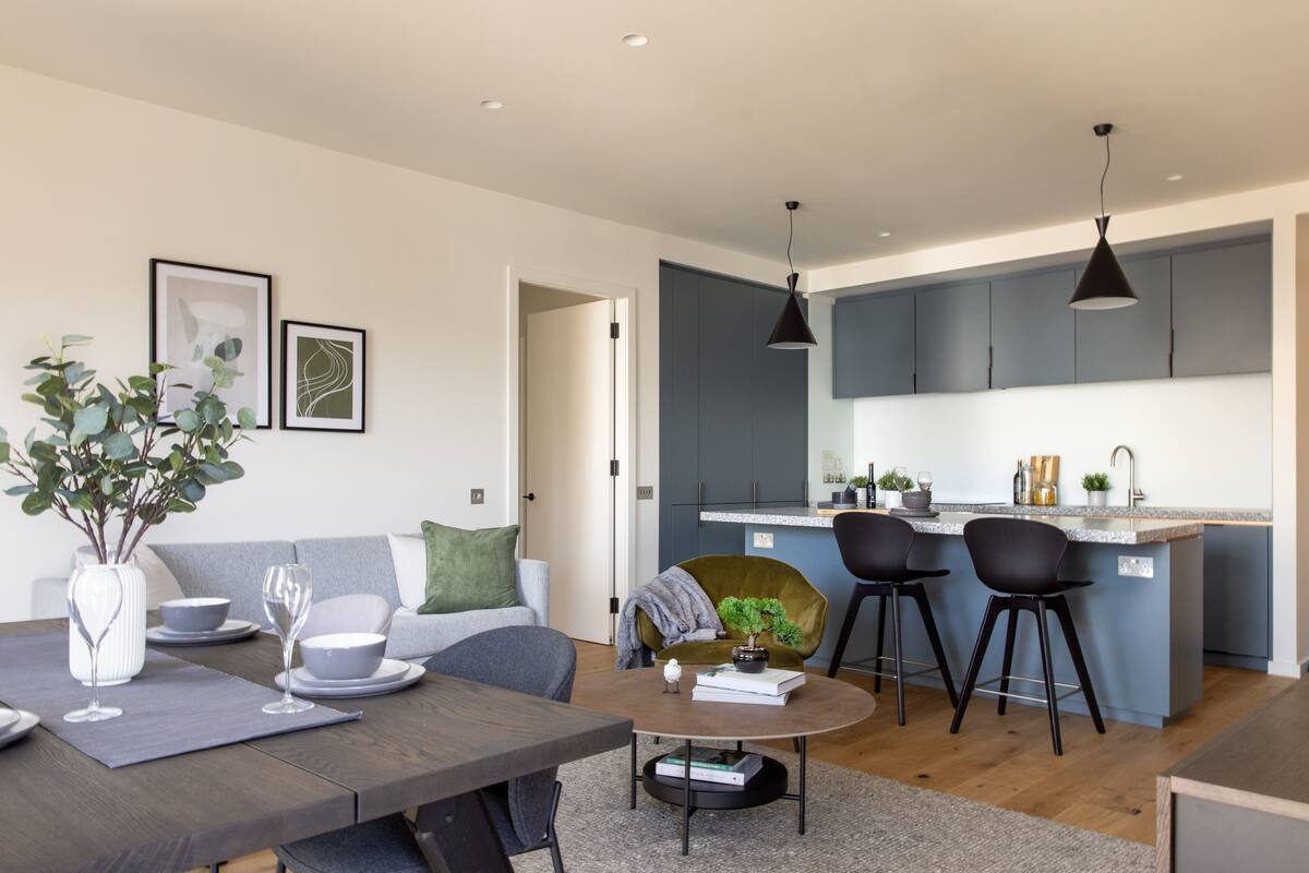 Une cuisine moderne avec des meubles gris, un îlot central et des tabourets de bar.