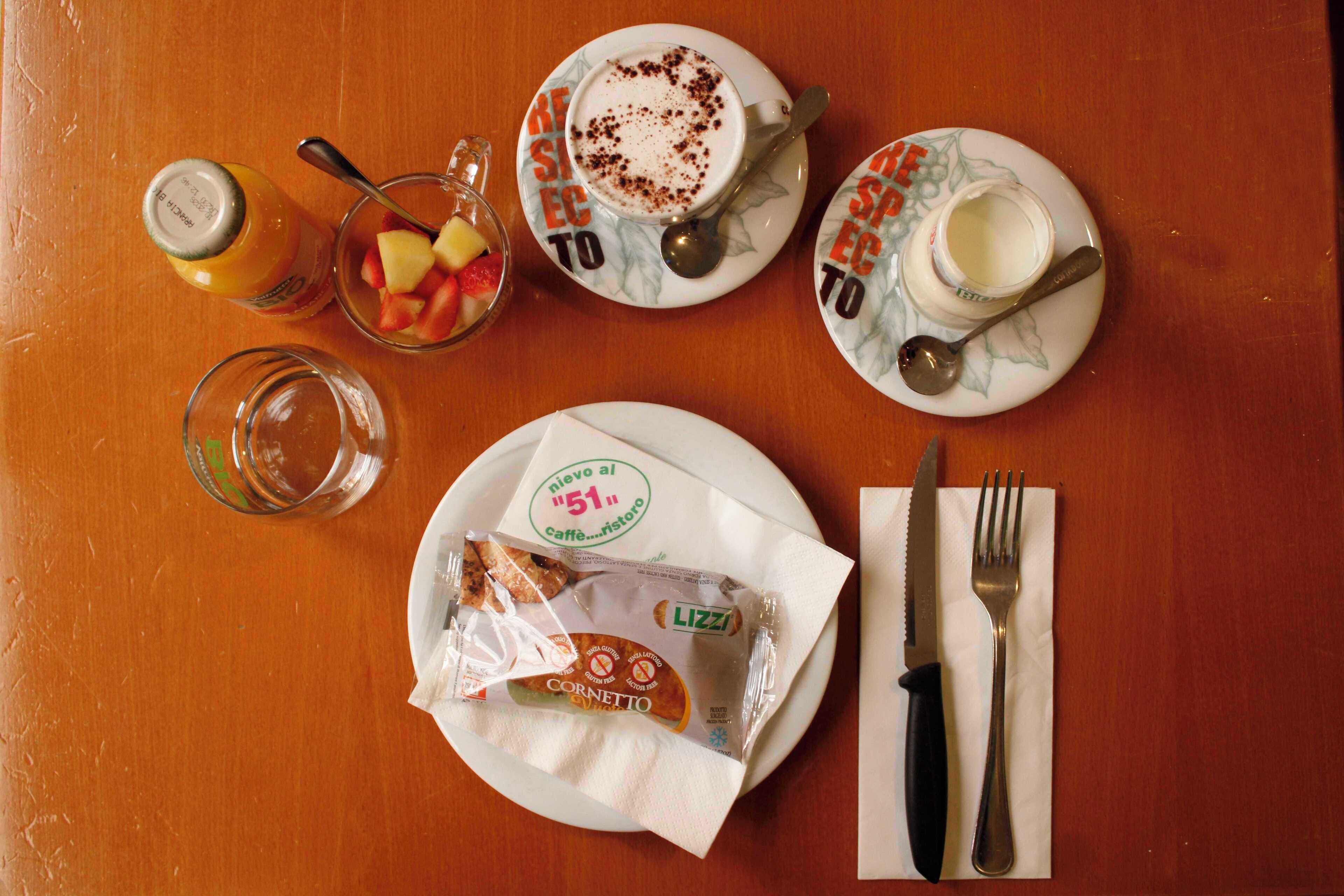 A table with a plate of food, a glass of juice, a cup of coffee, a fork, and a knife.