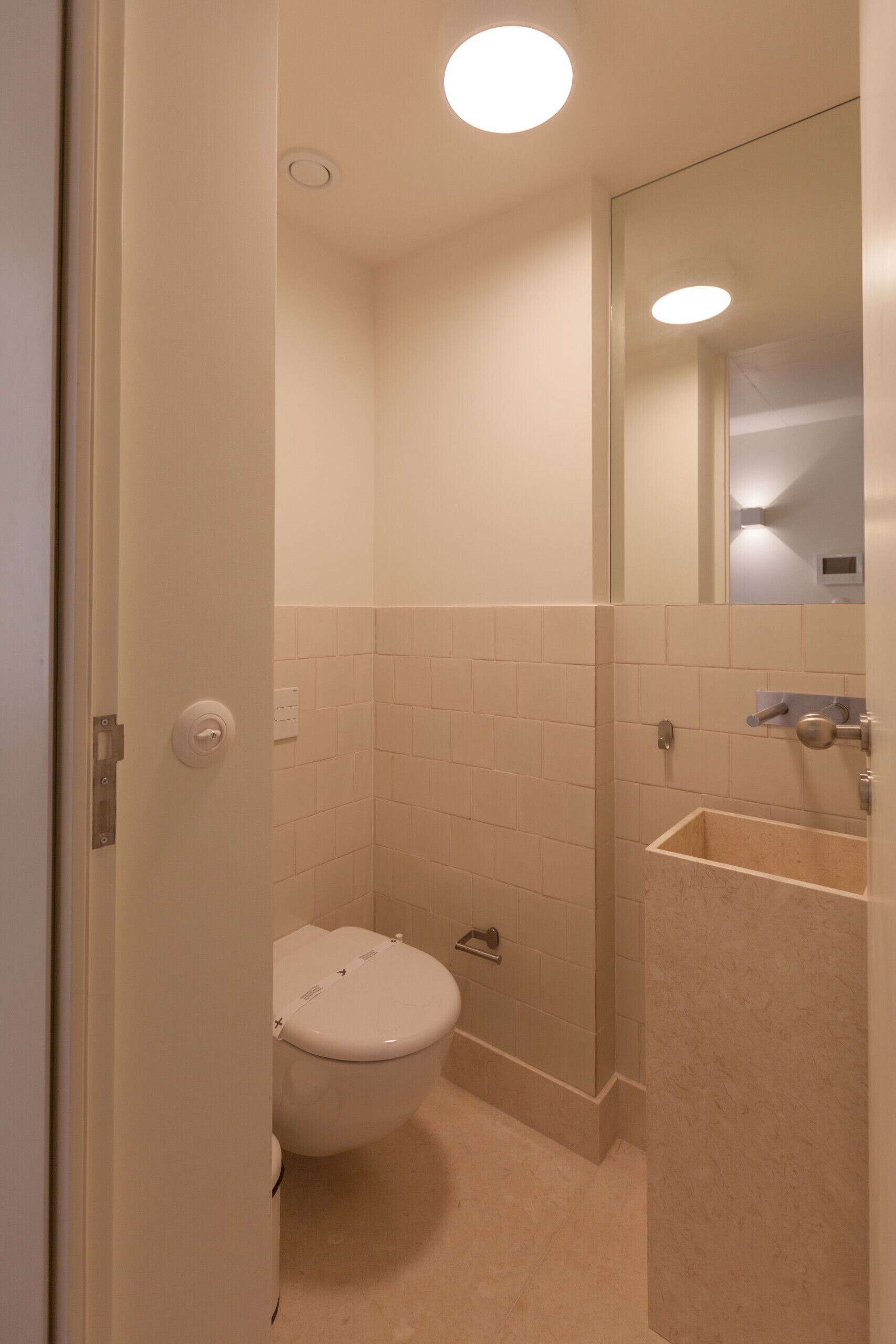 A small, modern bathroom with a toilet, sink, and mirror.