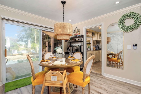 A dining area with a round table, yellow chairs, and a hanging light fixture.