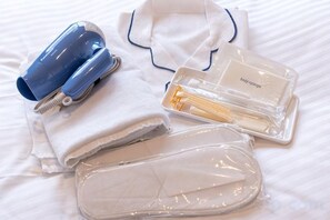 A neatly arranged set of toiletries on a bed, including a hairdryer, a bottle of lotion, and a toiletry bag. - FLYCAT HOTEL (Minokamo)