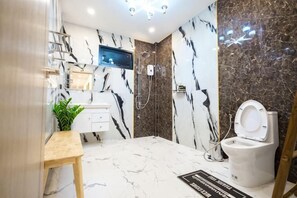A bathroom with a marble floor, a white toilet, a shower, and a wooden vanity. - Panita Poolvilla (Photharam)
