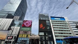 A cityscape with modern buildings, including a prominent HOKA sign. - Gracia Hotel (Osaka)