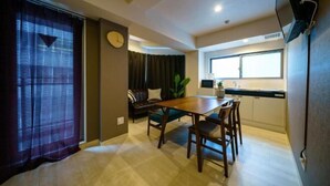 A modern kitchen with a dining area, a clock, and a TV mounted on the wall. - Gracia Hotel (Osaka)