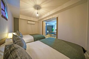 A hotel room with two beds, a ceiling light, a wall-mounted air conditioner, and a view of a dining area. - Gracia Hotel (Osaka)