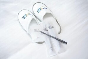 A pair of white slippers with 'CHIEF OF HOMES' text on them, placed on a white surface.