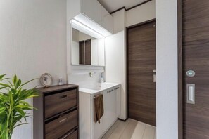 Ein Badezimmer mit Spiegel, Waschbecken, Schrank, Handtuchhalter und einer Tür.