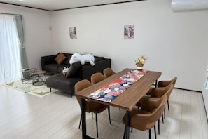 Ein modernes Wohnzimmer mit Esstisch, Sofa und Sesseln.