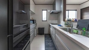 A modern kitchen with stainless steel appliances, a black floor mat with instructions, and a window providing natural light. - Yume Terrace at Yachimata (Yachimata)