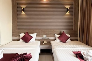 A hotel room with two beds, a wooden headboard, bedside lamps, a nightstand, and a small table. - Twin Hotel Kampot (Kampot)