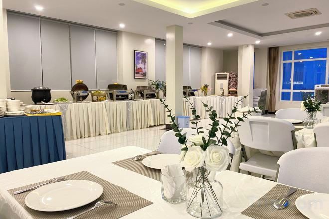 Un salón de banquetes con mesas dispuestas para comer, una zona de bufé y un amplio ventanal con vistas.