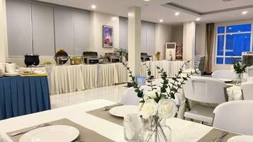 Un salón de banquetes con mesas dispuestas para comer, una zona de bufé y un amplio ventanal con vistas.