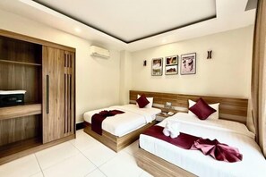 Quarto de hotel com duas camas, um guarda-roupa de madeira e ar condicionado fixado na parede.