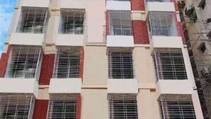 A multi-story building with a uniform facade, featuring a grid of windows with metal grilles. - China Inn Ltd (Dhaka)