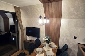 A dining area with a wooden table, chairs, a TV, and a decorative vase. - ZEN Luxury Houses & Spa Zlatibor (Municipality of Cajetina)