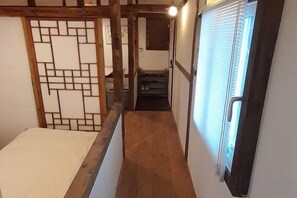Ein enger Korridor mit Holzboden, einer Schiebetür mit Fenster und einer traditionellen japanischen Schiebetür links.