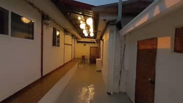A corridor with a wooden floor, a white wall, and a door on the right.