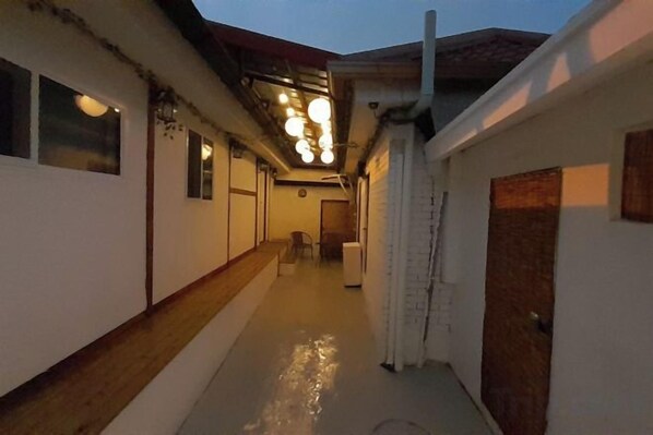 A corridor with a wooden floor, a white wall, and a door on the right.