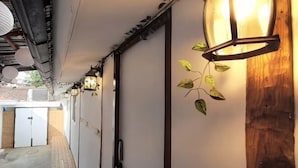 Ein Gang mit hängenden Laternen, einer Holzwand und einer Tür.