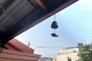 A hanging object, possibly a bag or container, under a structure with a metal roof. - [new] Hanok - Hyehwa 1937 (Seoul)