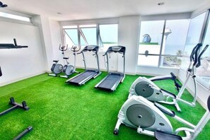 A gym with treadmills, stationary bikes, and a rowing machine on green turf. - The beach Bangsaen (Chon Buri)