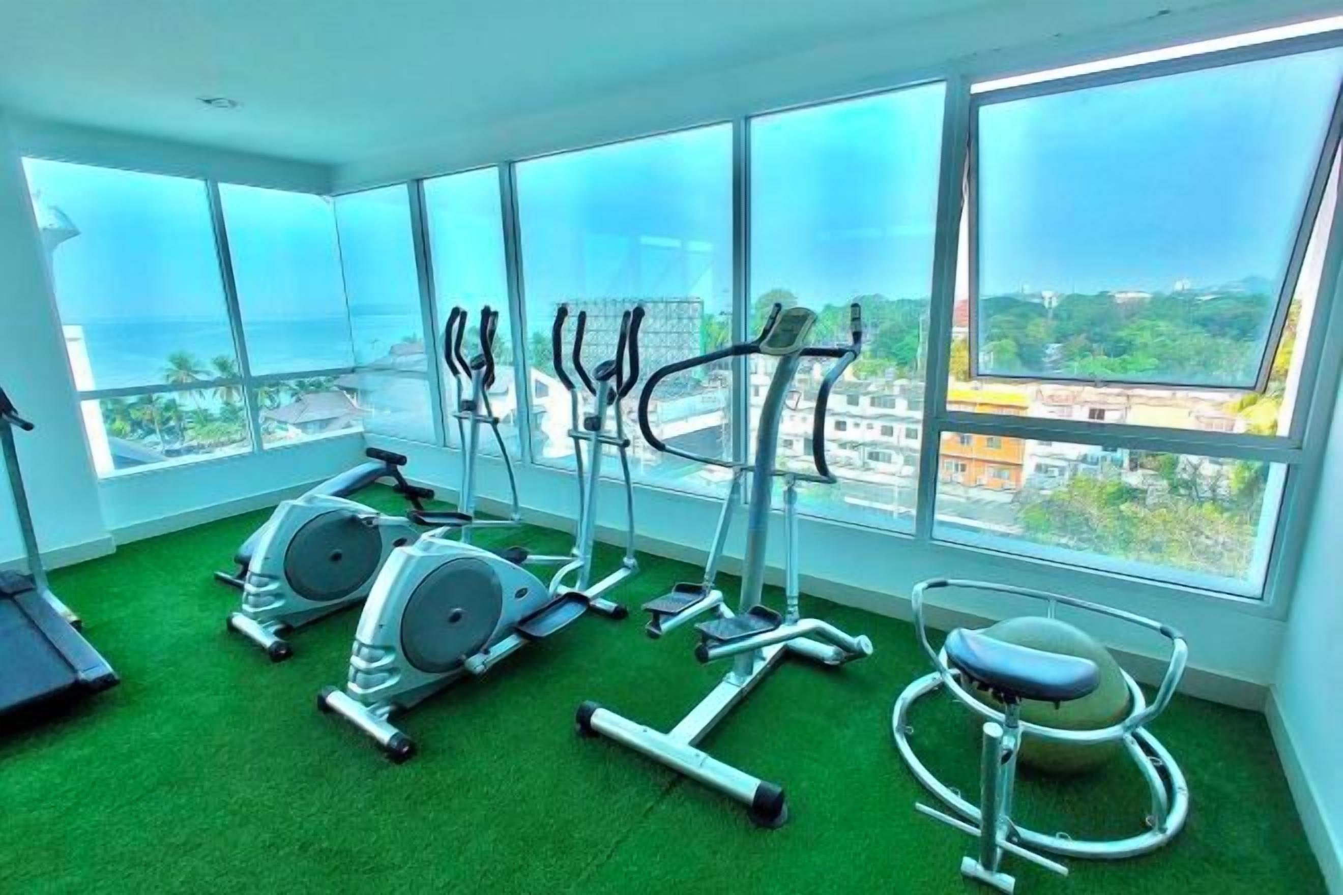 A gym with exercise equipment, large windows, and a view of the city.