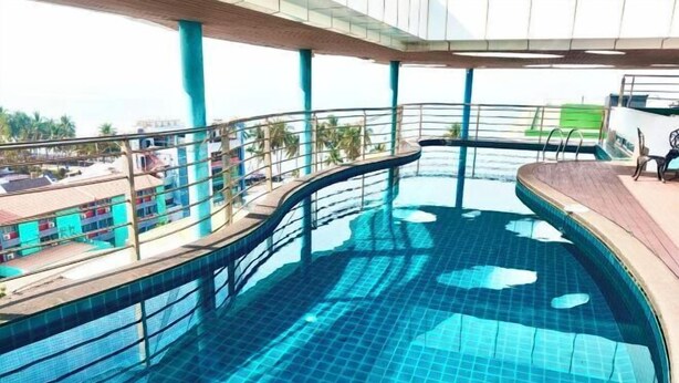 Una piscina de diseño curvo, rodeada por un recinto de vidrio y una terraza de madera.